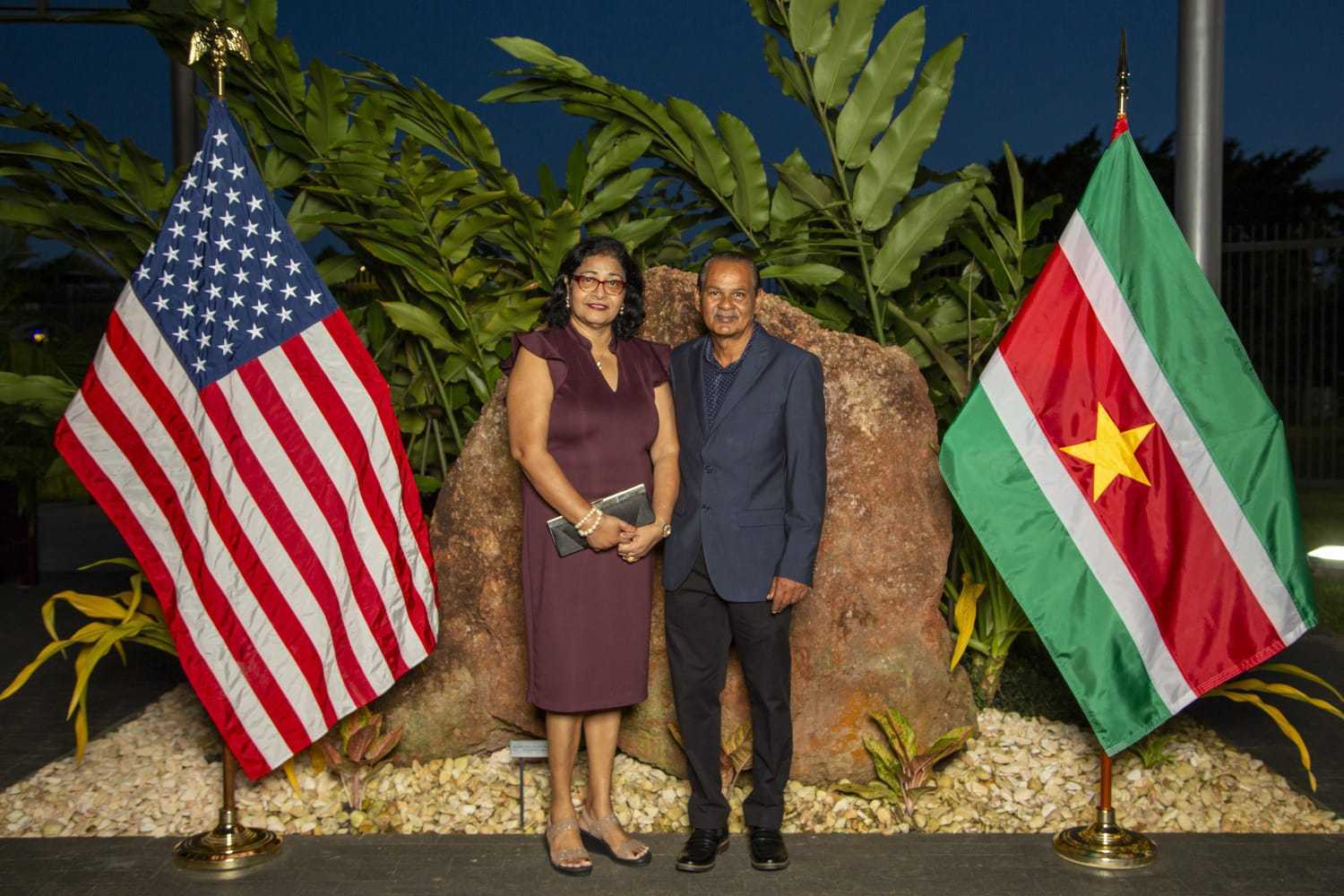 Mohamed Haroenkhan Abdul with his wife between the flags of the United States and Suriname